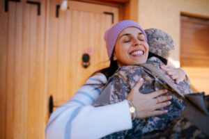 embracing her military spouse outside their front door